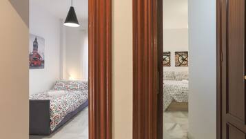 A bedroom with a bed, a desk, and a chair. There is a door leading to another room.