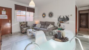 Un salon moderne comprenant un canapé, un fauteuil, une table basse et une table à manger en verre.