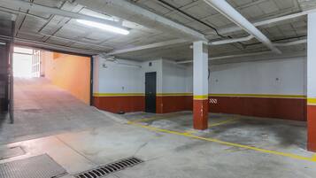 Een parkeergarage binnen met betonnen vloeren, muren in geel en rood en witte pilaren.