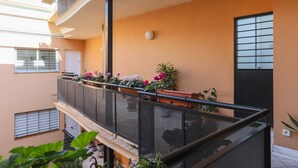 Un immeuble résidentiel à plusieurs étages, doté de balcons, de plantes en pot et d’une porte avec une fenêtre.