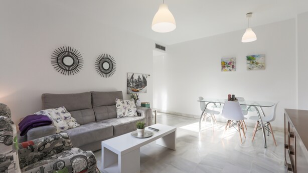 Un salon moderne comprenant un canapé, une table basse et un coin repas avec des chaises et une table en verre.