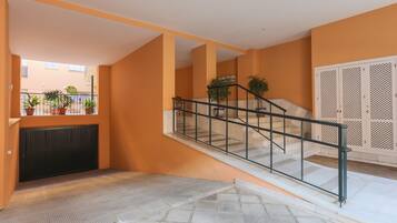 Un interior moderno con una escalera, plantas en macetas y vistas al exterior.