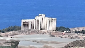 A coastal hotel with multiple floors, a large parking area, and a view of the sea. - Tartaga Penthouse (Adeje)