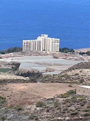 Ein Hotel an der Küste mit mehreren Etagen, einem großen Parkplatz und Meerblick.
