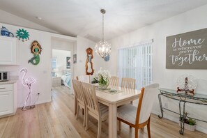 A dining area with a wooden table and chairs, a chandelier, and a wall sign saying 'Home is where we're together.' - Villa Willow Wood 3-Bedroom Home Private Pool (Inverness)