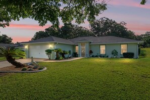 A two-story house with a garage, a well-maintained lawn, and a variety of plants and shrubs. - Villa Willow Wood 3-Bedroom Home Private Pool (Inverness)