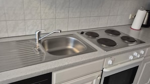 Una cocina con un lavaplatos de acero inoxidable, una estufa con cuatro quemadores y un lavavajillas.