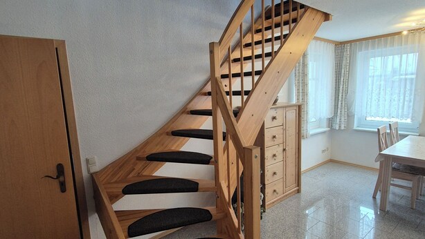 Una escalera de madera con escalones negros que conduce a una plataforma.
