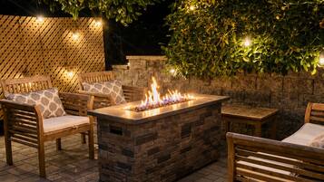 An outdoor patio with a fire feature, wooden furniture, and a stone wall.