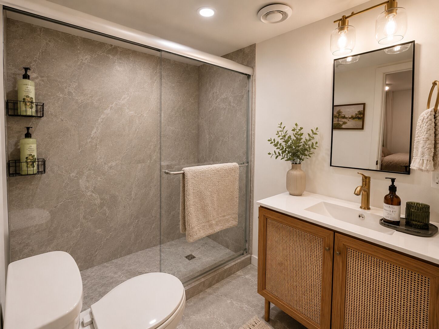 A modern bathroom with a glass shower enclosure, a white toilet, a wooden vanity with a mirror, and toiletries on the wall.