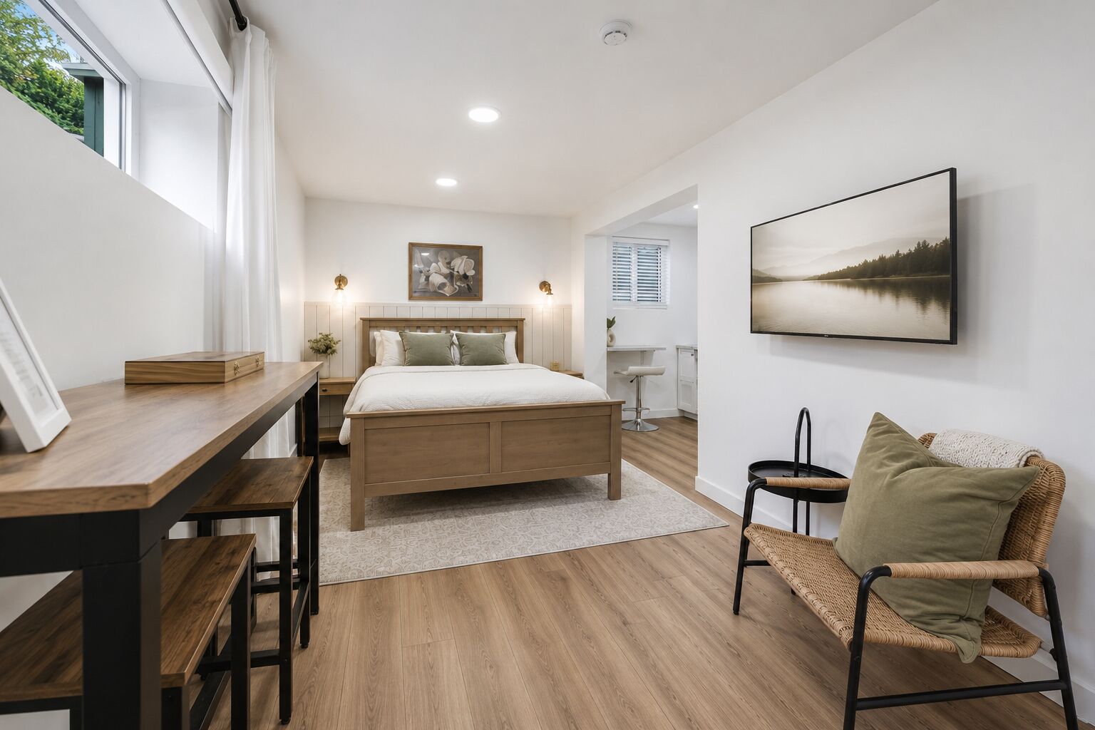 A bedroom with a bed, bedside tables, a desk, a chair, a framed picture, and a painting on the wall.