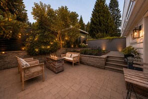 Een terras met tuinmeubilair, een vuurkuil en een stenen muur.