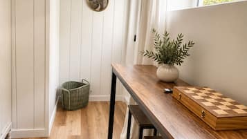 A compact kitchen with wooden flooring, a wooden table, a chessboard, and a potted plant.