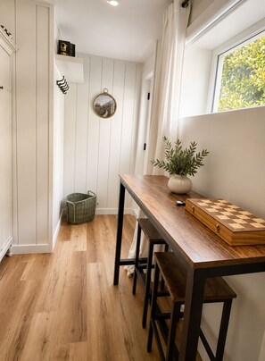 Une cuisine de taille réduite avec un plancher en bois, une table en bois, un jeu d’échecs et une plante en pot.