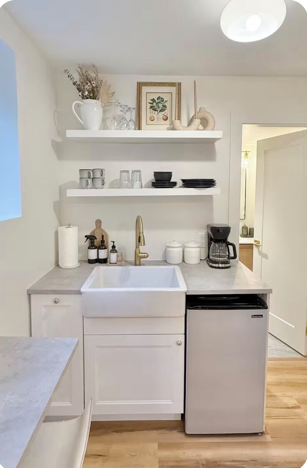 A modern kitchen with white cabinetry, a built-in dishwasher, and a coffee maker.
