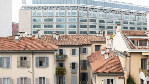 A row of traditional buildings with red-tiled roofs and shuttered windows, adjacent to a modern glass building with a grid-like facade. - Stunning two-bedroom flat in the centre of Milan (Milano)