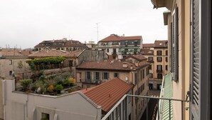 A view of a residential area with multiple buildings, including a house with a red-tiled roof and a balcony with potted plants. - Stunning two-bedroom flat in the centre of Milan (Milano)