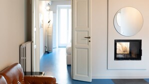 A hotel room with a white door, a round mirror on the wall, and a view of a hallway with a blue floor. - Stunning two-bedroom flat in the centre of Milan (Milano)