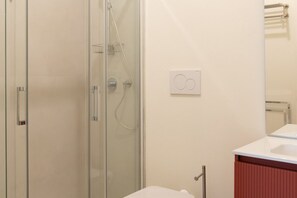 A modern bathroom with a glass shower enclosure, a white sink, and a red cabinet. - Stunning two-bedroom flat in the centre of Milan (Milano)