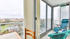 A balcony with a view of a residential area, a wooden chair, and two blue chairs. - Appartement 143 Résidence Bora Bora (Saint-Hilaire-de-Riez)