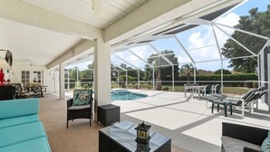 Un espacio al aire libre cubierto con piscina, sillas de descanso y una mesa con un farol.
