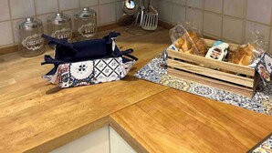 A kitchen with wooden cabinets, a tiled backsplash, and various kitchen items like jars, utensils, and bread. - Saraceno Holiday Home Piazza Indipendenza Palermo (Palermo)