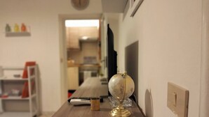 A wooden desk with a globe, a remote, and a mug in a room with a clock on the wall. - Saraceno Holiday Home Piazza Indipendenza Palermo (Palermo)