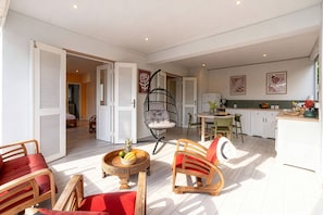 An open-plan living and dining area with a kitchen, a hanging chair, and a dining table with chairs. - Granada (Le Diamant)