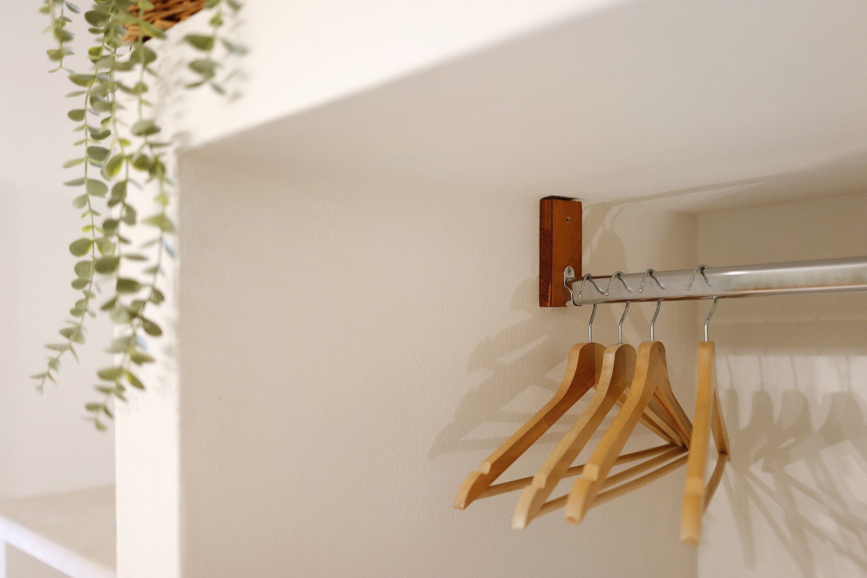 Une tige métallique avec des supports en bois, fixée contre un mur.