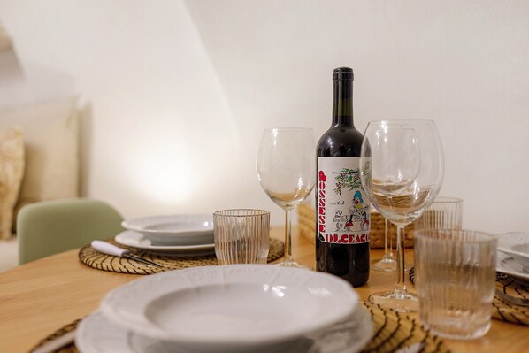A dining table with a bottle of wine, glasses, and plates.