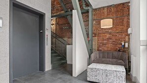 Um interior moderno com escada, porta cinza e um banquinho estampado.