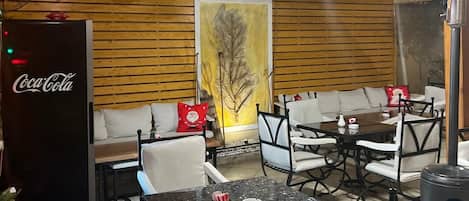 A cozy restaurant interior with wooden walls, a large leaf mural, and seating arrangements including tables and chairs.