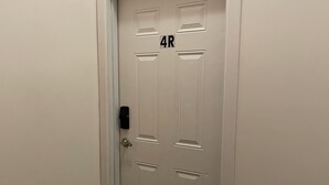 Eine weiße Tür mit der Nummer 4R, einem Klingel und einer Fußmatte.