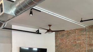Ein modernes Wohnzimmer mit einem Flachbildfernseher, zwei Ledersesseln, einem kleinen Tisch und einem blauen Sofa.