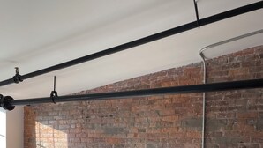 Ein Schlafzimmer mit Backsteinwand, einem Bett mit weißer Bettwäsche, zwei Nachttischen mit Lampen und einem modernen Deckenbau.