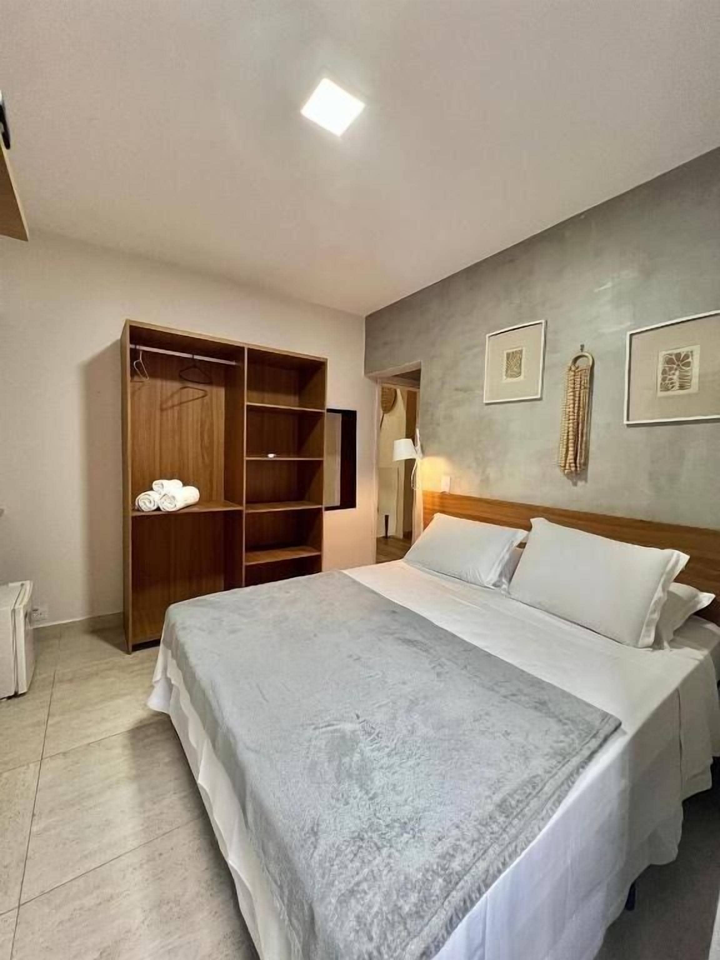 A bedroom with a bed, wardrobe, and wall-mounted artwork.