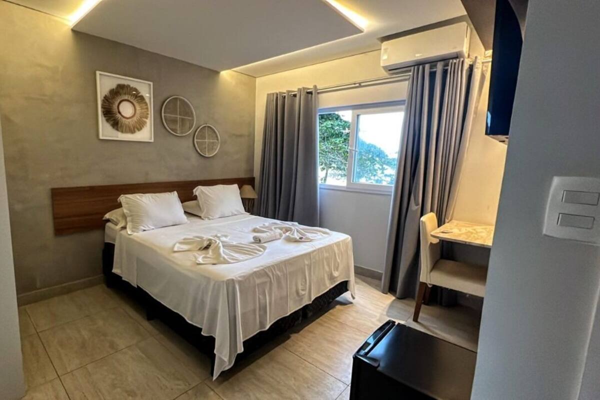 Une chambre d’hôtel avec un lit, un bureau et une fenêtre avec des rideaux.