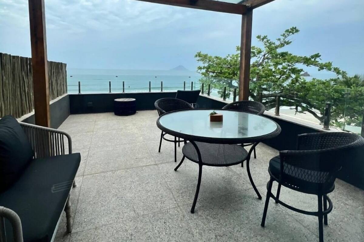 Une terrasse avec une table et des chaises en verre, un canapé et une vue sur la mer.