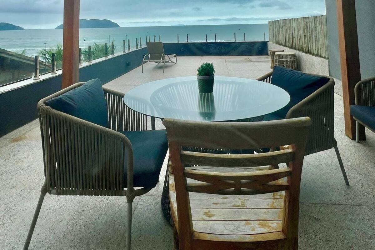 Une table ronde en verre, des chaises, une plante en pot et une vue sur la mer.