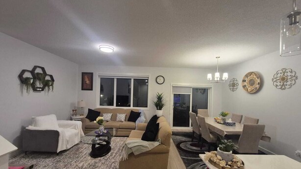 A modern living room with a sofa, coffee table, and dining area. - Welcome to Sunny’s Homes! This spacious upper-level unit in West Edmonton. (Edmonton)