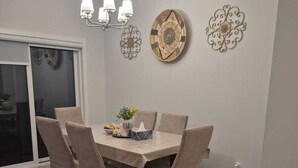 A dining area with a round table, six chairs, a chandelier, decorative wall art, and a rug. - Welcome to Sunny’s Homes! This spacious upper-level unit in West Edmonton. (Edmonton)
