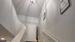 A staircase with carpeted steps, a white handrail, and a wall-mounted light fixture. - Welcome to Sunny’s Homes! This spacious upper-level unit in West Edmonton. (Edmonton)