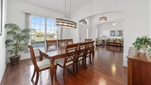 A spacious dining area with a large table and chairs, a hanging light fixture, and a view through large windows. - Villa S&G: Spacious 5 bedroom, family vacations (Inverness)
