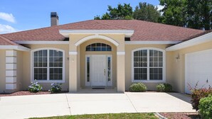 A two-story house with a beige facade, a red-tiled roof, and a front entrance with a white door. - Villa S&G: Spacious 5 bedroom, family vacations (Inverness)