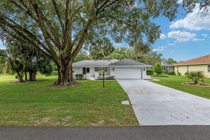 A single-story house with a front yard, a driveway, and a garage. - Soak Up the Sun: 3BR Pool & Jacuzzi Home Near Inverness (Inverness)