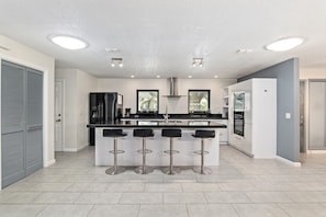 A modern kitchen with a central island, bar stools, and built-in appliances. - Soak Up the Sun: 3BR Pool & Jacuzzi Home Near Inverness (Inverness)