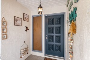 Una entrada amb temàtica costanera, porta blava, decoració mural i llum penjant.