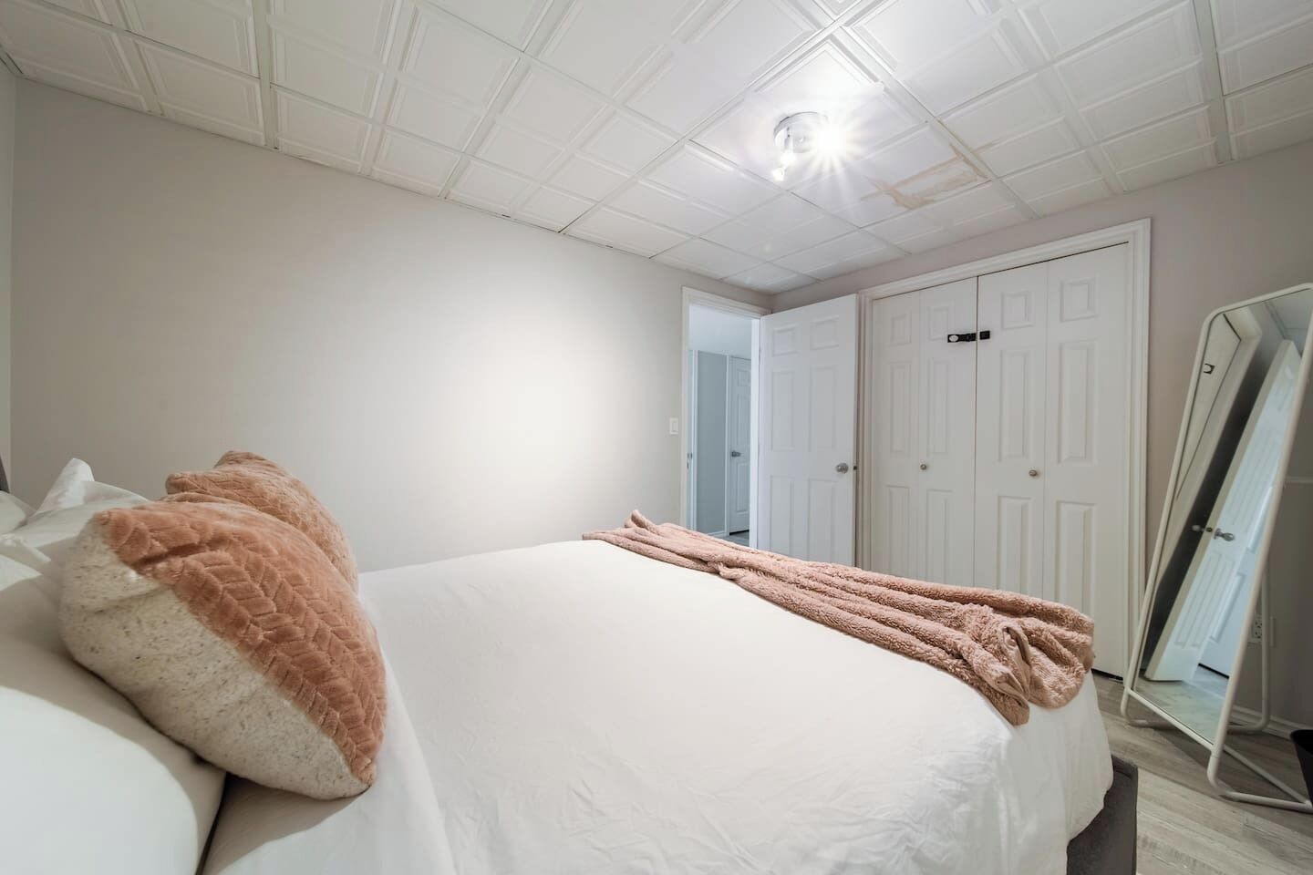 Un dormitorio con cama, espejo y puerta.