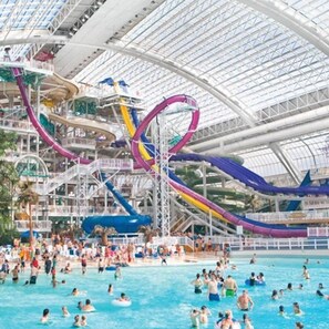 Un parque acuático interior grande con varias toboganes y piscinas.