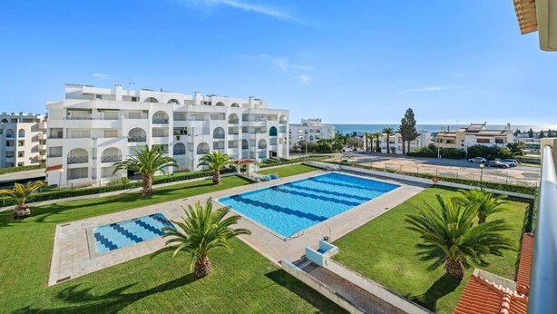 A hotel with a swimming pool, palm trees, and a view of the sea. - 1-Bedroom Apartment with Garden View, Shared Pool, Wi-Fi & Air Conditioning (Porches)